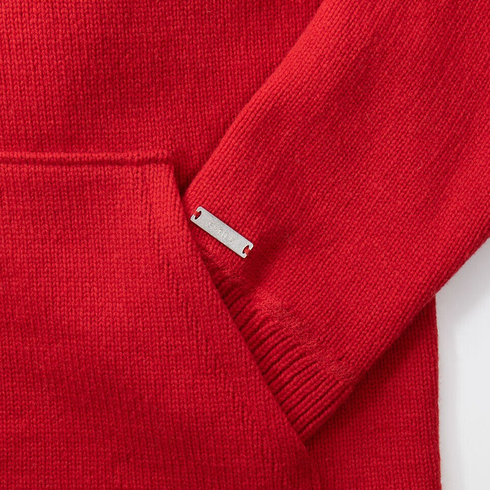 Röd stickad hoodie för dam och herr med en stor magficka och en metallabel vid ärmslutet